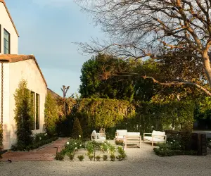 Garden pool with a stone wall, hedges, and a blue umbrella